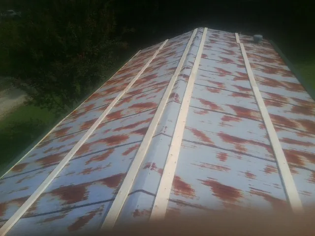 Rusted metal roof panels with new wood purlins before replacement — Storm Damage Roof Repair in East Smithfield by Roofing Brothers