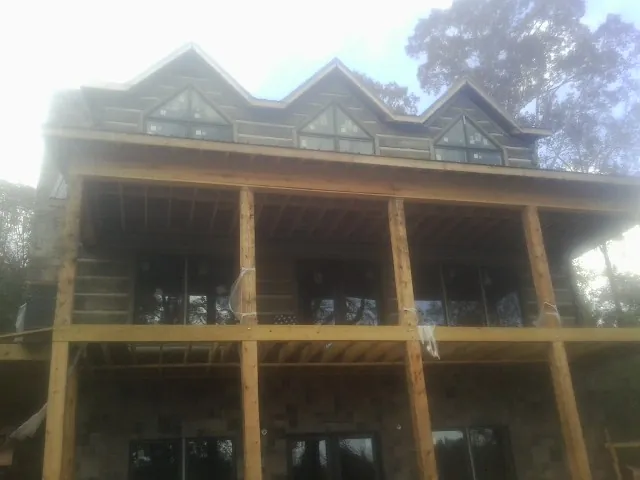 Dormers and porch framing on a large log home under construction — Roof Coating work by our crew in East Smithfield