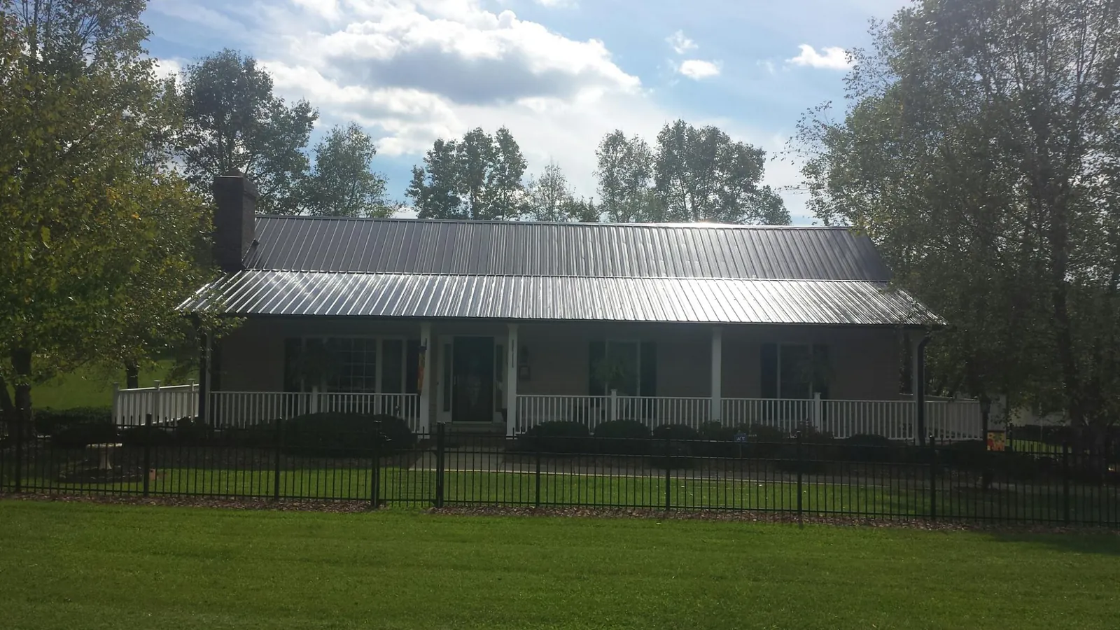 Gray metal roof on a brick ranch with a full width front porch — Gutter Guard Installation work by our crew in East Smithfield