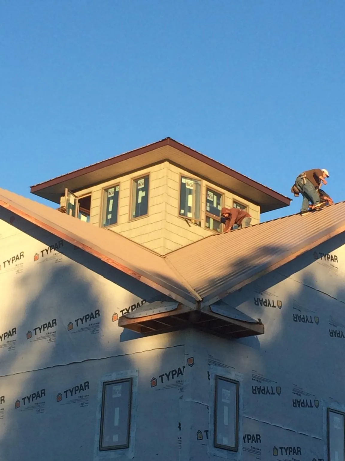 Roofers working around a rooftop cupola on a new metal roof at sunset — Roof Waterproofing in East Smithfield by Roofing Brothers